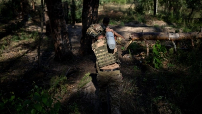 Ein ukrainischer Soldat trägt eine Granate in Richtung einer Haubitze an der Frontlinie bei Lyman. (Foto: Bram Janssen/AP/dpa)