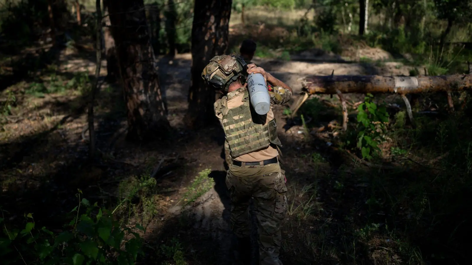 Ein ukrainischer Soldat trägt eine Granate in Richtung einer Haubitze an der Frontlinie bei Lyman. (Foto: Bram Janssen/AP/dpa)