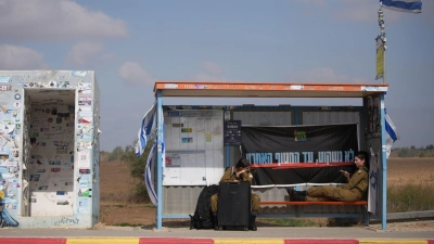 An einem Busbahnhof nahe der Grenze zum Gazastreifen warten israelische Soldatinnen auf den Transport. (Foto: Ohad Zwigenberg/AP/dpa)