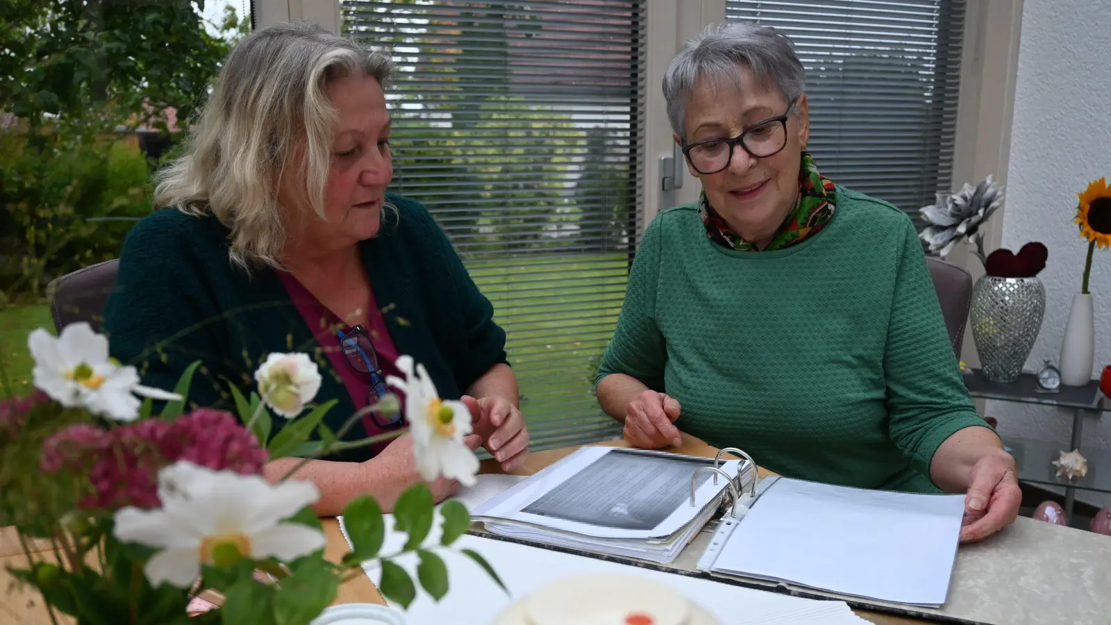 Evi Siebachmeyer (links) und Käthe Körner sehen sich einen Ordner mit Dokumenten aus zehn Jahren Flüchtlingshilfe an. (Foto: Anna Beigel)
