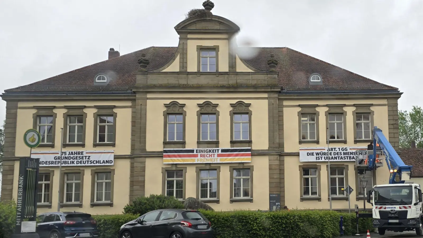 Drei Banner wurden jetzt mit Hilfe einer Hebebühne an der Fassade des Herriedener Rathauses angebracht. Sie erinnern an das Inkrafttreten des Grundgesetzes vor 75 Jahren. Geplant ist, die Zitate von Passagen der Verfassungsordnung von Zeit zu Zeit zu wechseln. (Foto: Stadt Herrieden/Anja Schwander)