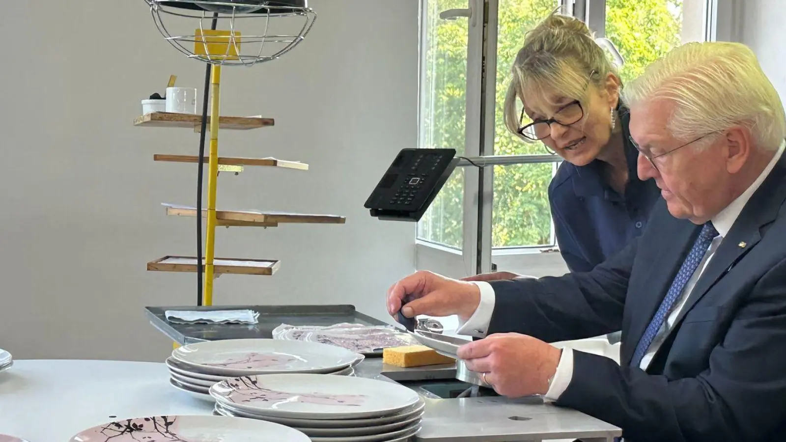 Bundespräsident Frank-Walter Steinmeier (r) lässt sich bei seinem Besuch der Firma Seltmann in Weiden von Porzellandruckerin Mariella DeLuca die Dekoration eines Tellers erläutern. (Foto: Ute Wessels/dpa)