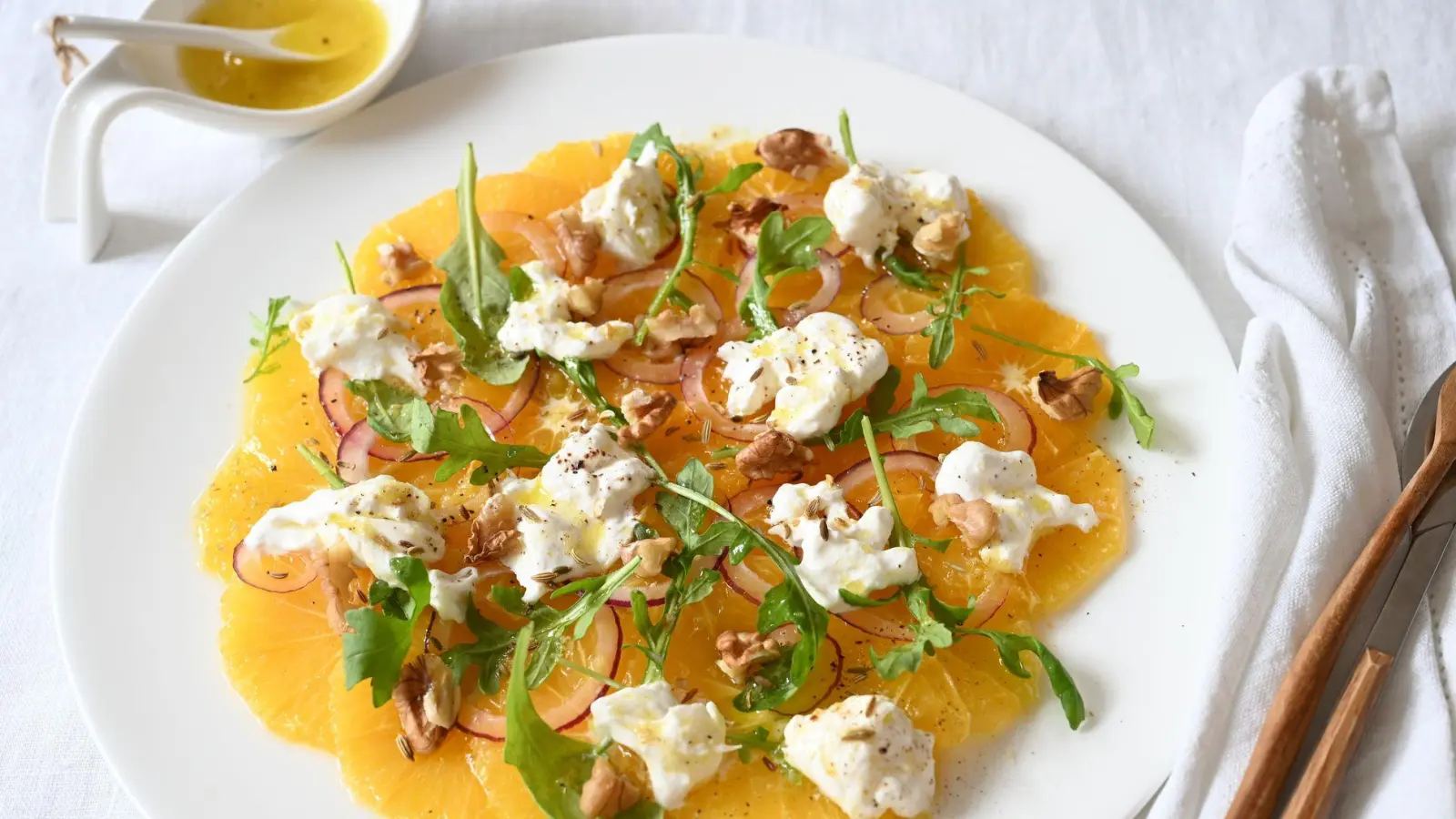 Erinnert an das Strahlen der Sonne: Das Orangen-Carpaccio ist nicht nur fruchtig, sondern verzaubert auch mit einem herzhaften Knoblauch-Kick. (Foto: Julia Uehren/loeffelgenuss.de/dpa-tmn)