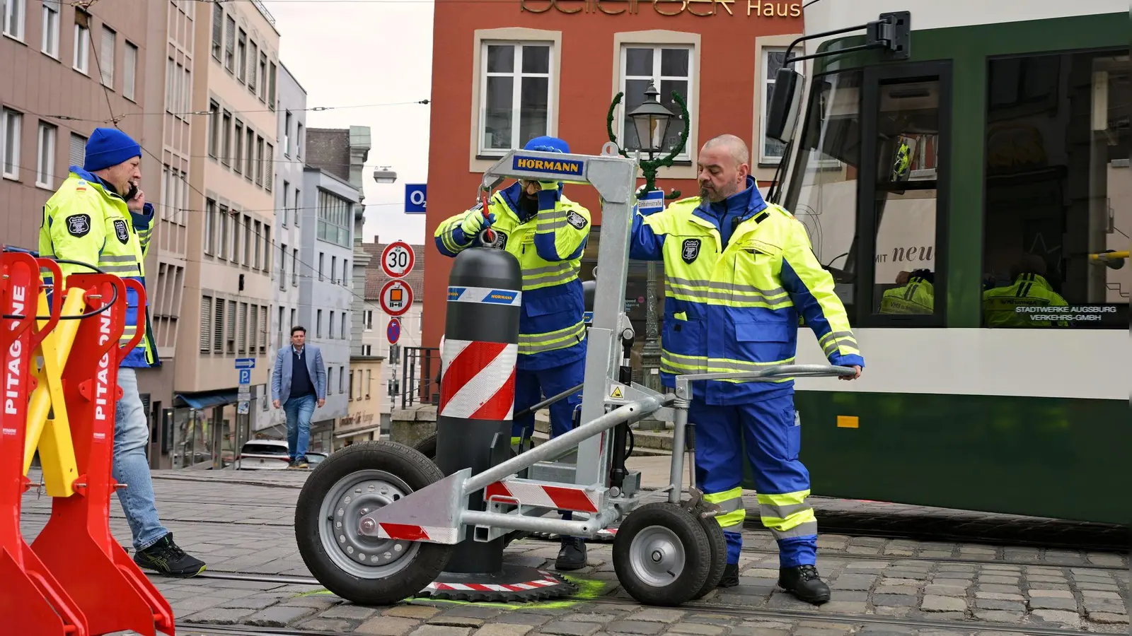 Zu den Hauptverkehrszeiten müssen Sicherheitsmitarbeiter neben dem Augsburger Christkindlesmarkt jede Stunde dutzendfach schwere Poller bewegen, damit die Straßenbahnen durchfahren können. (Foto: Malin Wunderlich/dpa)