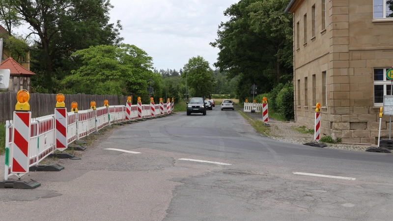Die Kurve bei der alten Schlossgaststätte (rechts) gilt als Nadelöhr für den Verkehr, vor allem während der Schulbuszeiten. In diesem Bereich wird mit der Sanierung der Staatsstraße in Klosterdorf auch eine Ampel errichtet. Die Barken grenzen aktuell einen Fußgängerbereich ab, in dem es künftig einen regulären Gehweg geben soll. (Foto: Andreas Reum)