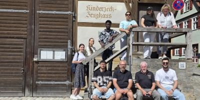 Wie regionales Brauchtum gepflegt wird, erfuhren Schülerinnen und Schüler der Berufsintegrationsklasse bei einem Besuch im Zeughaus der Kinderzeche. Einen Einblick in das Heimatfest gab Festspieler Robert Hippelein (vorne, Zweiter von rechts). Die jungen Leute wurden von den Lehrkräften Claudia Geißler-Kraft (auf der Treppe rechts) und Dr. Martin Nipp (vorne, Zweiter von links) begleitet.  (Foto: Markus Weinzierl)