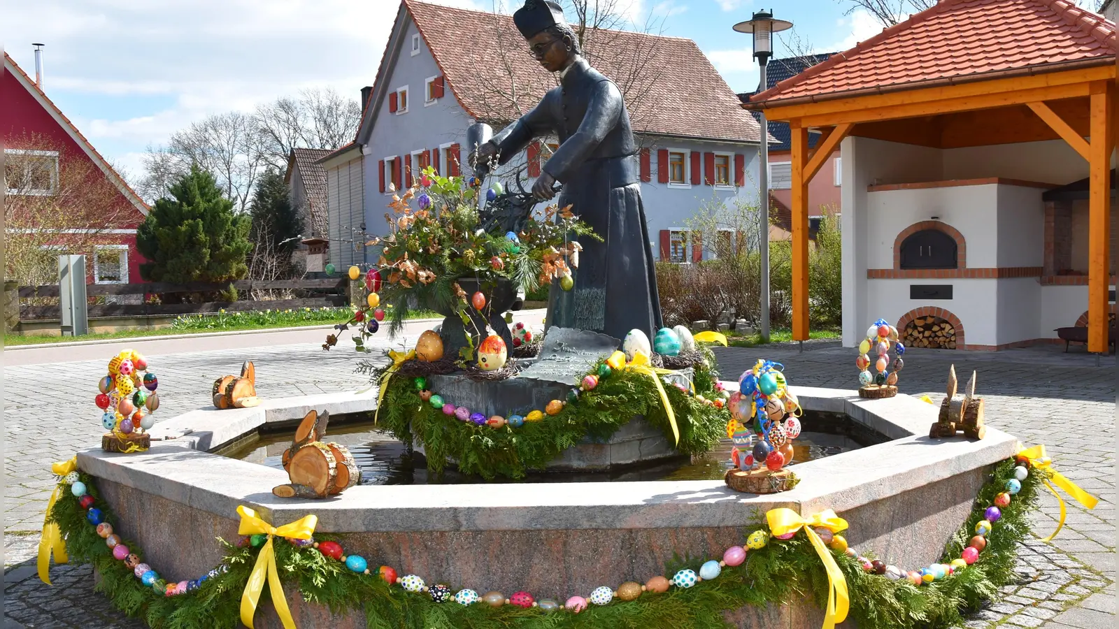 Mitglieder des Dorfvereins „Elbersroth Rundum” haben den Pfarrer-Heumann-Brunnen auf dem Dorfplatz mit 700 Eiern von Wachteln, Hühnern und Emus - allesamt selbst ausgeblasen und bemalt – geschmückt. Zusammen mit Girlanden wurden die auf einer langen Schnur aufgereihten bunten Eier an den Spitzen des achteckigen Wasserbeckens befestigt. Kleine Osterhasen aus Holz und die kunstvoll mit örtlichen Motiven bemalten Emu-Exemplare sind auf dem Brunnensockel platziert. Ein großer bunter Osterstrauß in der Schüssel der Pfarrer-Heumann-Figur krönt den Osterbrunnen in Elbersroth. (Foto: Werner Wenk)