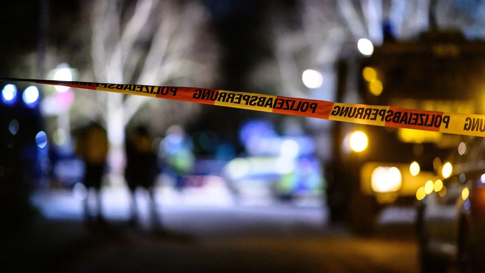 Ein Flatterband der Polizei ist vor Einsatzfahrzeugen am Tatort zu sehen. (Foto: Swen Pförtner/dpa)