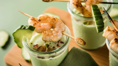 Eine kalte Suppe erfrischt an warmen Tagen - wie diese aus Gurken, Buttermilch und Basilikum, getoppt mit Garnelenspießen, Chiliflocken und Cayennepfeffer. (Foto: Christin Klose/dpa-tmn)