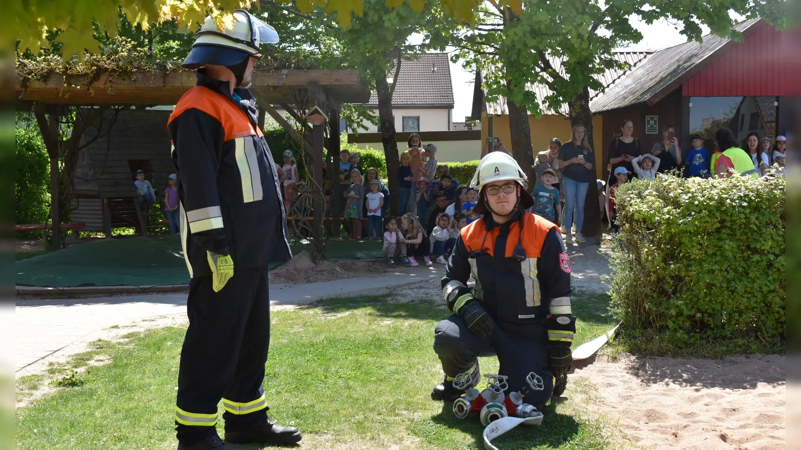 Wie die Feuerwehrleute bei der Übung eine Wasserversorgung aufbauten, interessierte die Mädchen und Buben des Kindergartens, die das Geschehen aus sicherer Entfernung verfolgten. (Foto: Erich Herrmann)