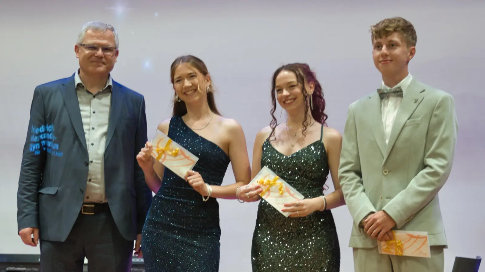 Studiendirektor Norbert Zips mit den drei Besten des Jahrgangs, Emmy Pfab, Nele Reumschüssel und Ben Dreßel (von links). (Foto: Christoph Lange)