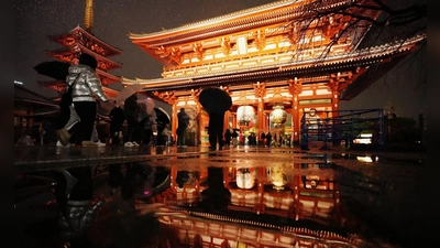 Der Sensoji-Tempel spiegelt sich in einer Pfütze, als Menschen zum Neujahrsgebet in Tokio ankommen. (Foto: Hiro Komae/AP/dpa)