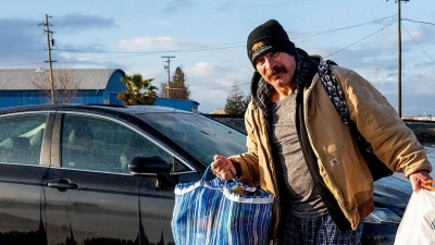 Ein Mann trägt im Januar in Merced, Kalifornien, Habseligkeiten aus seinem überfluteten Haus. (Foto: Noah Berger/AP/dpa)