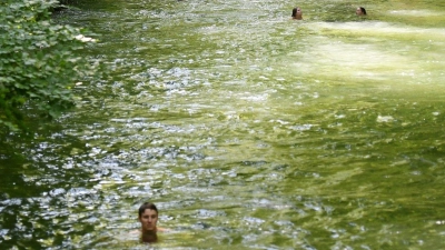 Eisbachschwimmer lassen sich im Eisbach durch den Englischen Garten treiben, zurück zum Einstiegspunkt gehts mit der Tram oder zu Fuß. (Foto: Angelika Warmuth/dpa)