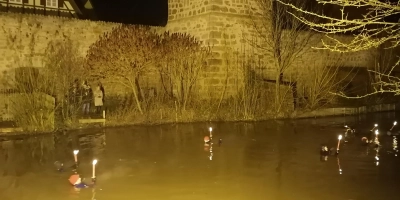 Vor Dinkelsbühls Stadtmauer als imposanter Kulisse: Bei einer Wassertemperatur um die sechs Grad legten die Fackel-Schwimmer rund einen Kilometer in der Wörnitz zurück. (Foto: Friedrich Zinnecker)