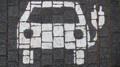 Ein Symbol markiert einen Parkplatz mit einer öffentlichen Ladesäule für Elektroautos. (Foto: Marco Rauch/dpa)