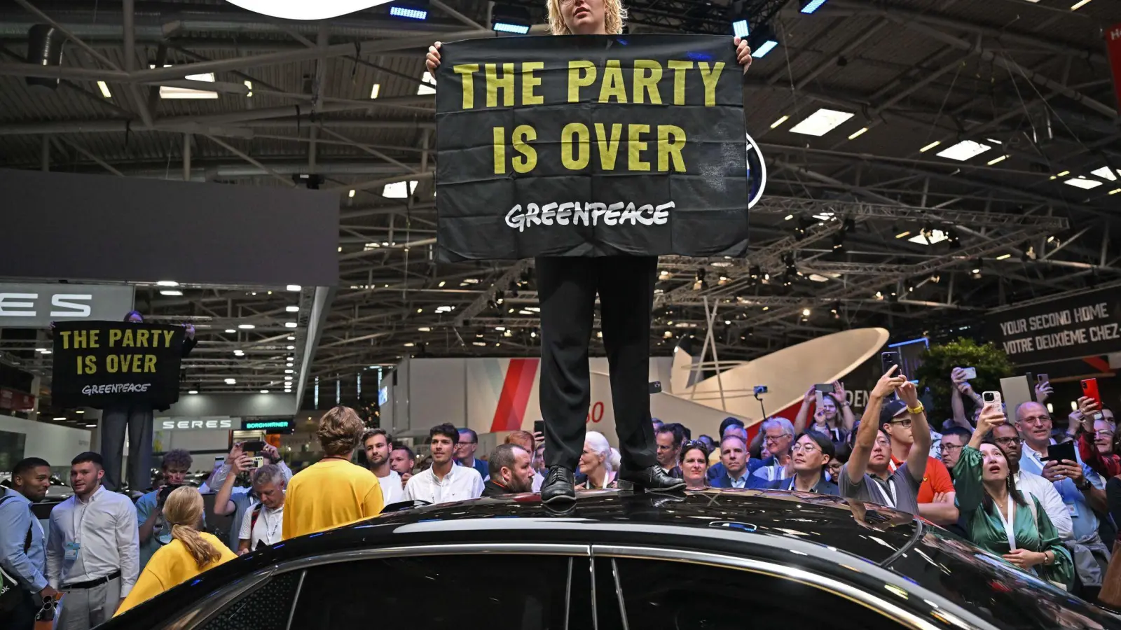 Eine Greenpeace-Aktivistin bei der Eröffnung der IAA auf dem Dach eines ausgestellten Autos. (Foto: Sven Hoppe/dpa)