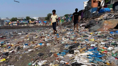 Menschen spazieren am Strand des Badhwar Park im indischen Mumbai an Plastikmüll vorbei. (Archivbild) (Foto: Rajanish Kakade/AP/dpa)