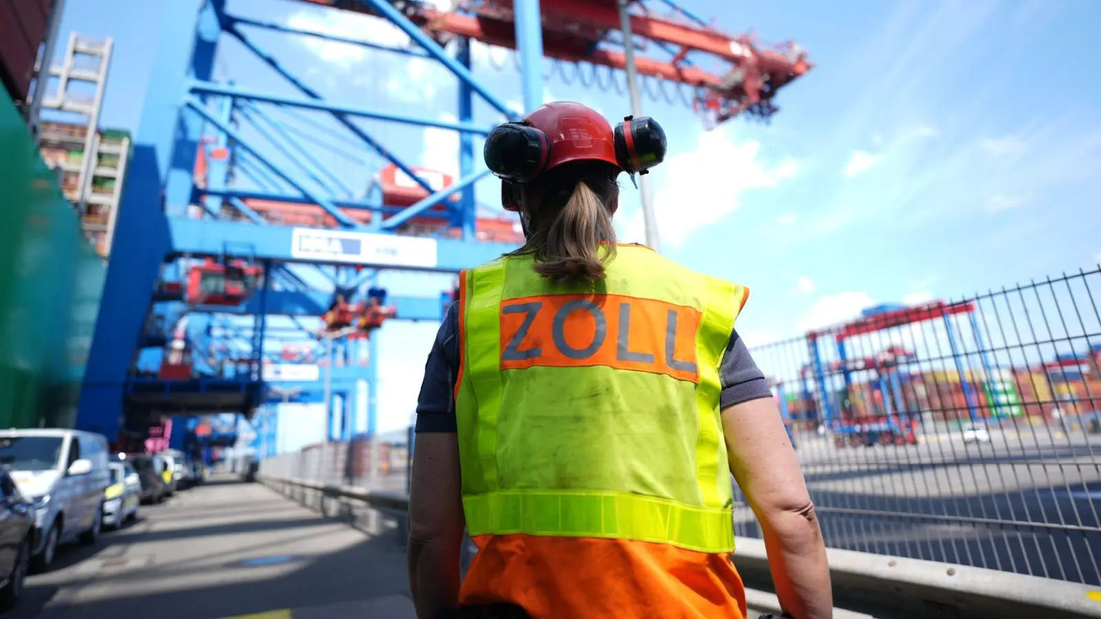 Eine Zollbeamtin steht neben einem Containerschiff im Hamburger Hafen.  (Foto: Marcus Brandt/dpa)