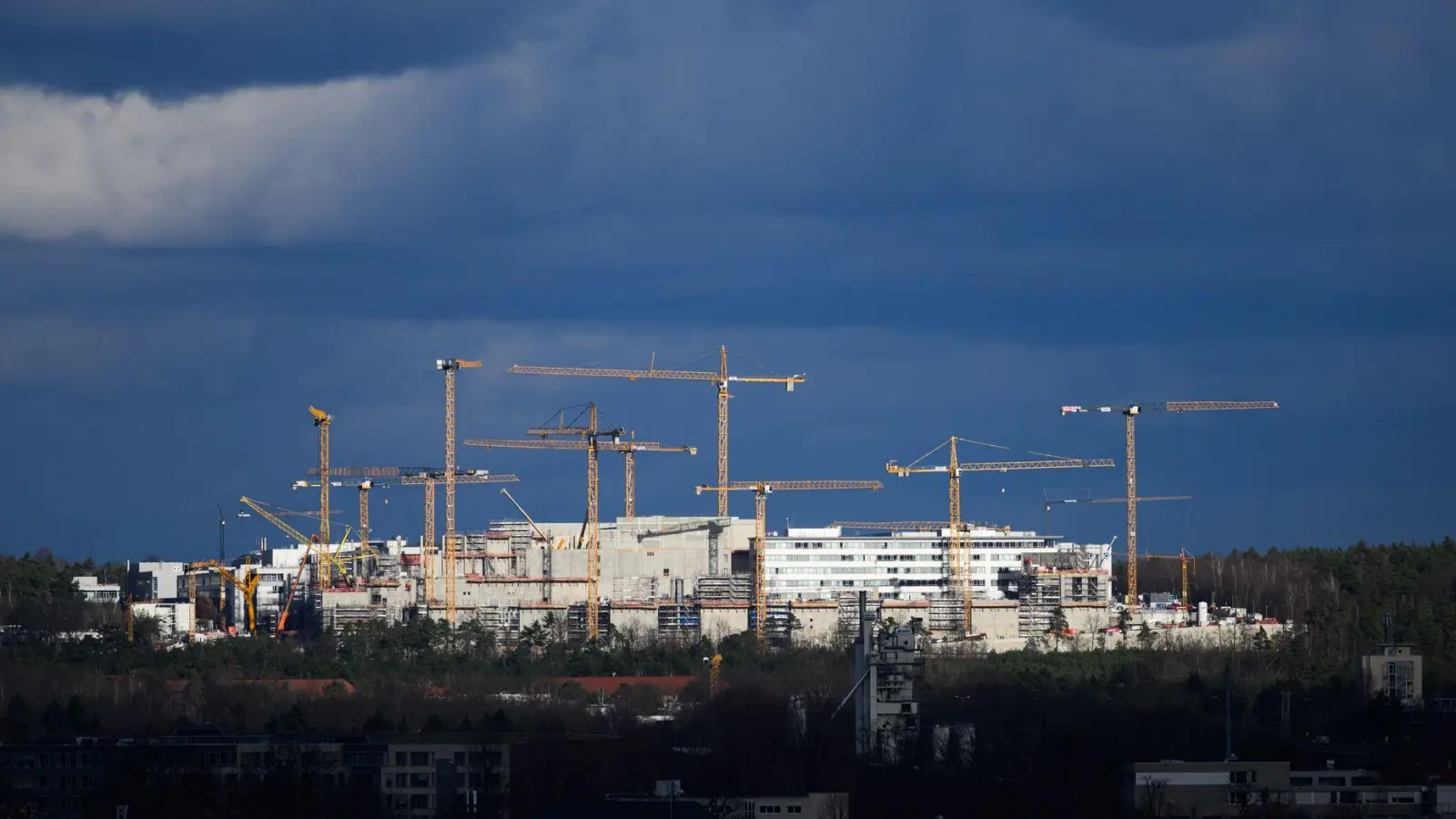 Dunkle Wolken über der Fabrikbaustelle von Infineon in Dresden. Der Halbleiterkonzern profitiert vom schwachen Euro, doch potenzielle Zollkonflikte machen Sorgen. (Archivbild) (Foto: Robert Michael/dpa)