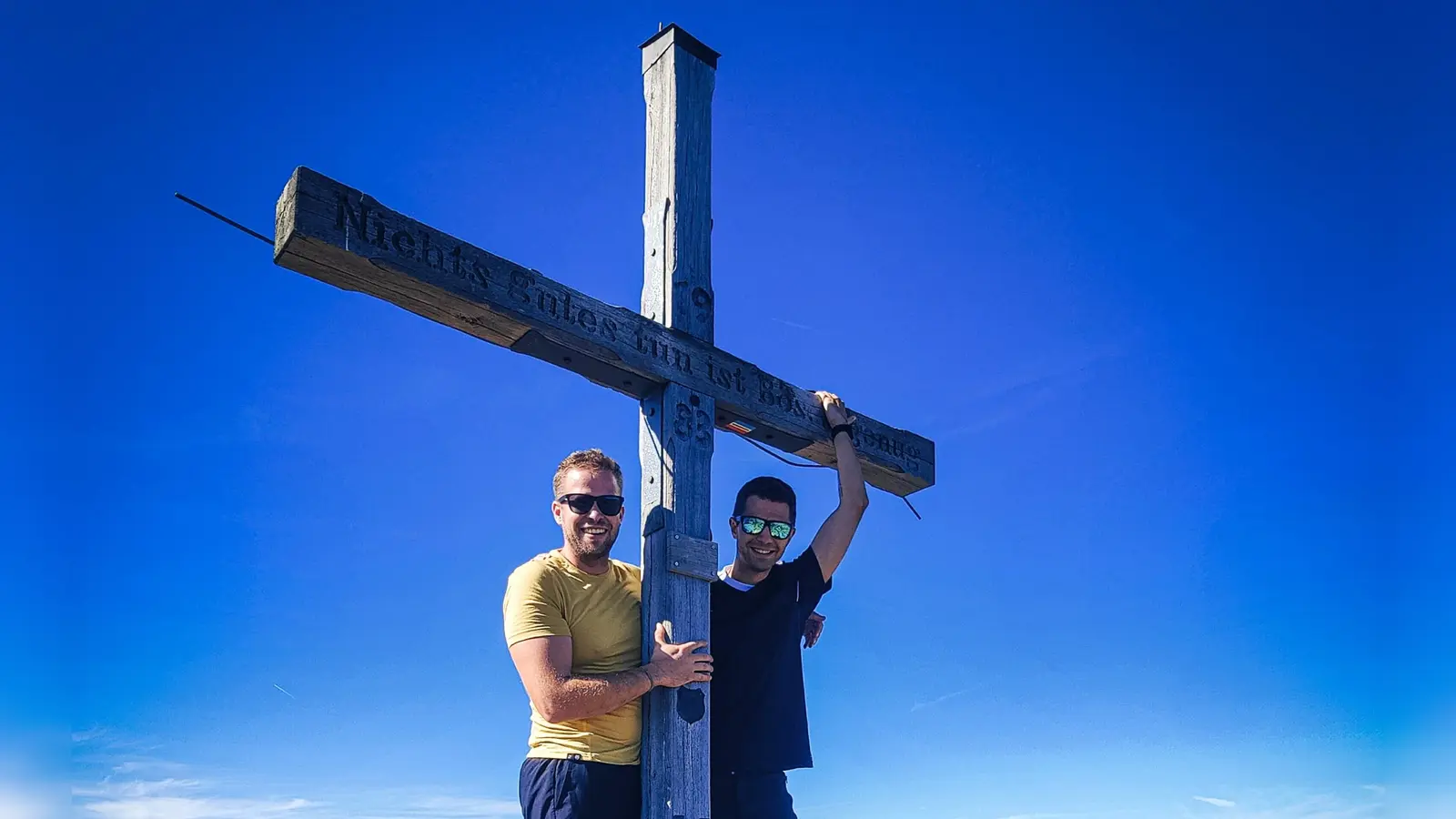 Das 1983 von Bergfreunden aus dem Rothenburger Raum auf den Rosskopf-Gipfel gesetzte Kreuz steht noch. Steffen Heidingsfelder (links) und Franz Lindner haben es in gutem Zustand vorgefunden. Der ins Holz eingeritzte Sinnspruch lautet „Nichts Gutes tun ist Böses genug“. (Selbstauslöserfoto: Steffen Heidingsfelder)