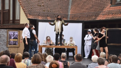 Jedermann (Jaap Swaminathan, auf dem Tisch) weiß sich Gehör zu verschaffen, während der Tod (Steve Sträßer, im weißen Anzug) geduldig auf ihn lauert. (Foto: Andreas Reum)