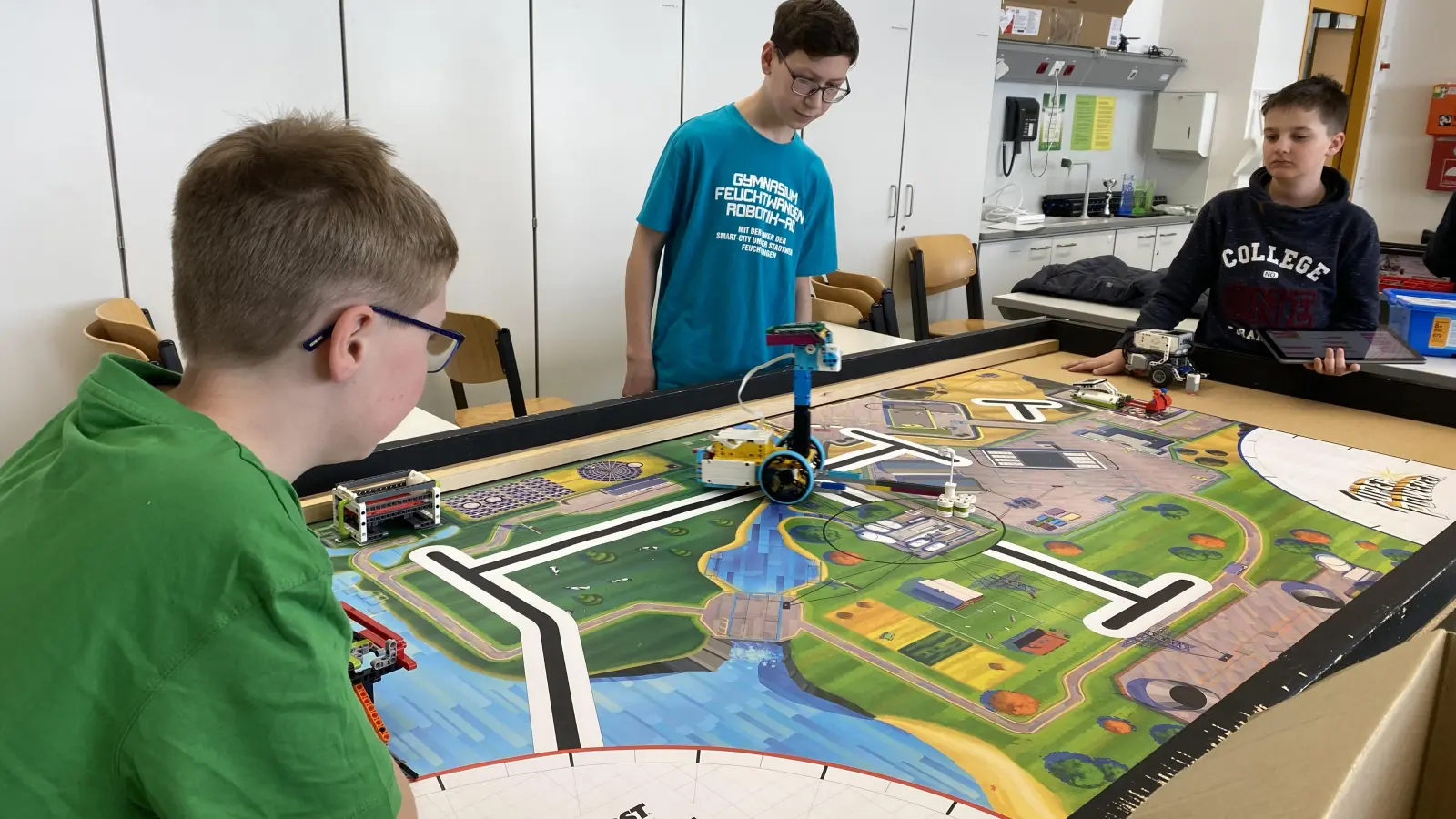 Die Schüler Felix Weiskopf, Björn Wambach und Paul Kandert (von links) testen einen von ihnen selbst gebauten Roboter, der kleine Legoteilchen einsammeln kann. (Foto: Janne Feder)