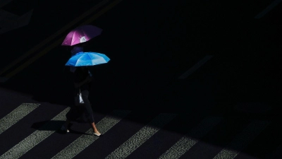 Hitzewelle in China: Fußgänger schützen sich mit Regenschirmen vor der Sonne an einem ungewöhnlich heißen Tag. (Foto: Andy Wong/AP)