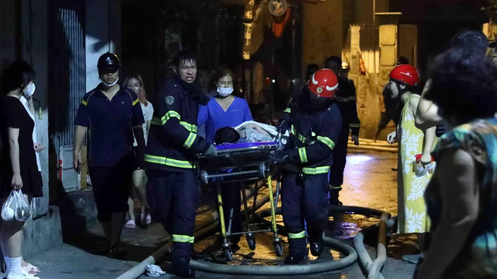 Rettungskräfte tragen eine Person aus dem brennenden Gebäude in Hanoi. (Foto: Pham Trung Kien/VNA/AP/dpa)