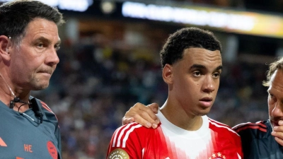 Jamal Musiala musste nur 25 Minuten nach seiner Einwechselung angeschlagen vom Platz, begleitet von Teamarzt (r) und Physiotherapeut.  (Foto: Sven Hoppe/dpa)
