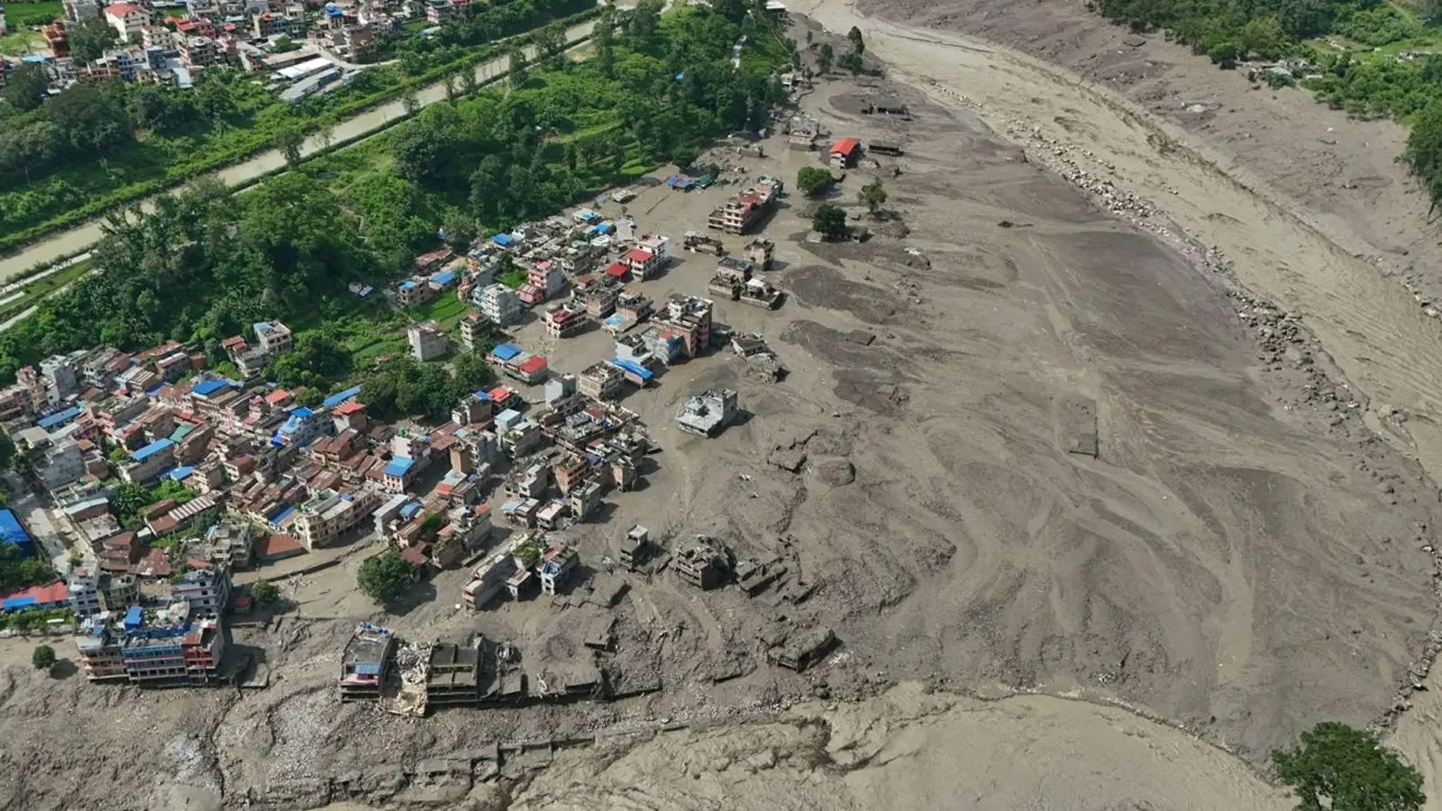 Nach Sturzfluten im nepalesischen Distrikt Nuwakot stehen beschädigte Häuser gefährlich nahe an den angeschwollenen, mit Treibgut verstopften Ufern des Trishuli-Flusses. (Foto: Niranjan Shrestha/AP/dpa)