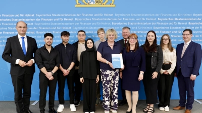 Die Berufsschulklasse des Schulzentrums Ansbach-Triesdorf mit Schulleiter Dietmar Gaffron (rechts), Dr. Rudolf Neumaier, Geschäftsführer des Bayerischen Landesvereins für Heimatpflege (fünfter von rechts) und Lehrkräften bei der Übergabe des Förderbescheids durch Finanz- und Heimatminister Albert Füracker (links).  (Foto: StMFH/Christian Blaschka)