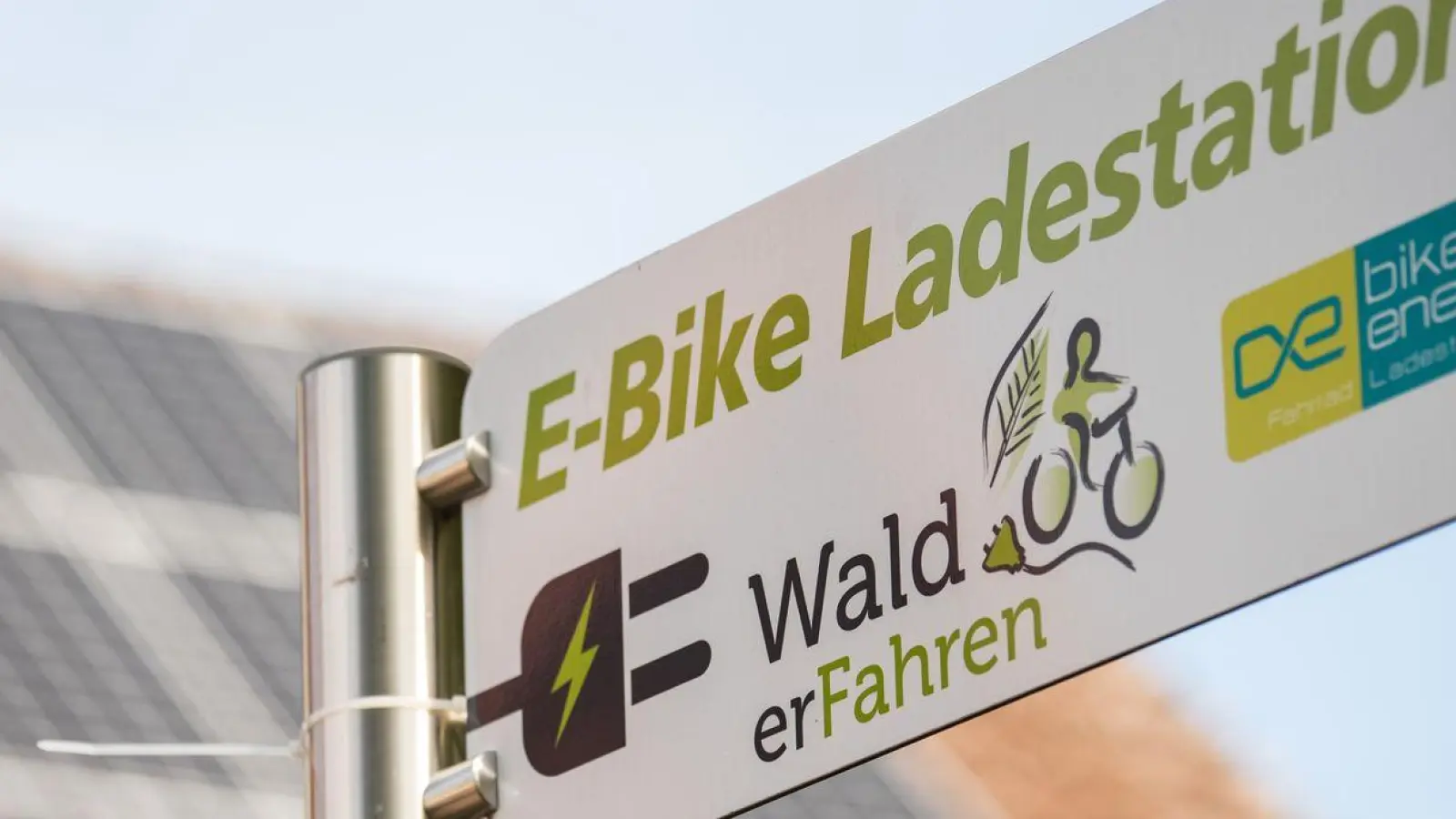 Vor dem Rathaus ist ein Schild mit dem Hinweis auf eine „E-Bike Ladestation” zu sehen. (Foto: Nicolas Armer/dpa)