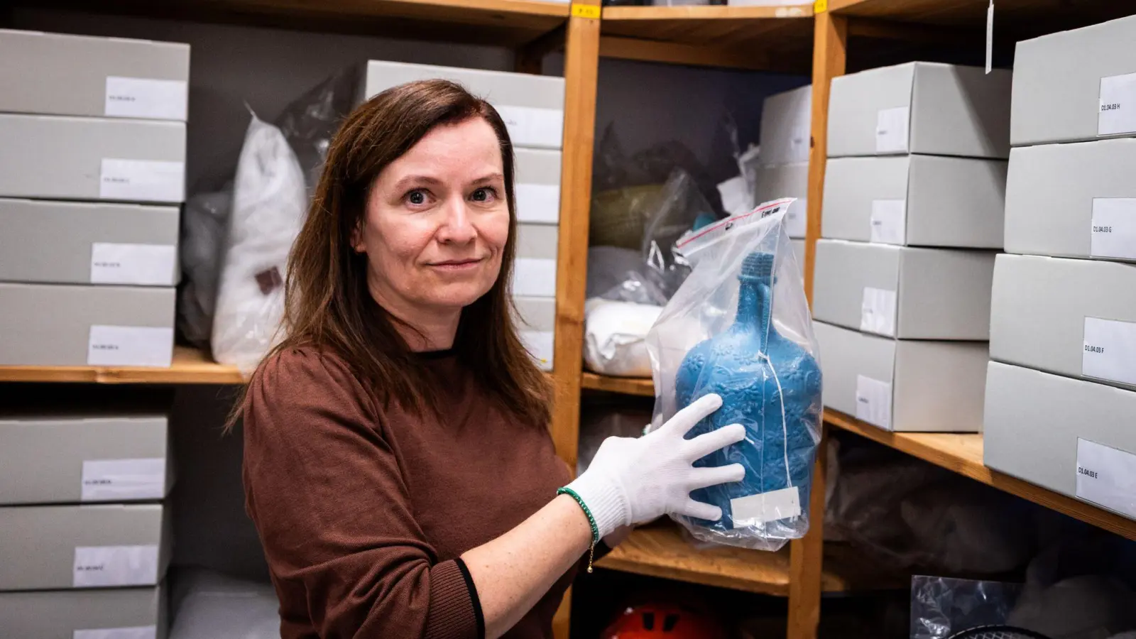 Bengü Kocatürk-Schuster vom Dokumentationszentrum und Museum über die Migration in Deutschland (DOMiD) zeigt eine Trinkflasche, die von Türken einst auf ihre erste Reise nach Deutschland mitgenommen wurde. (Foto: Christian Knieps/dpa)