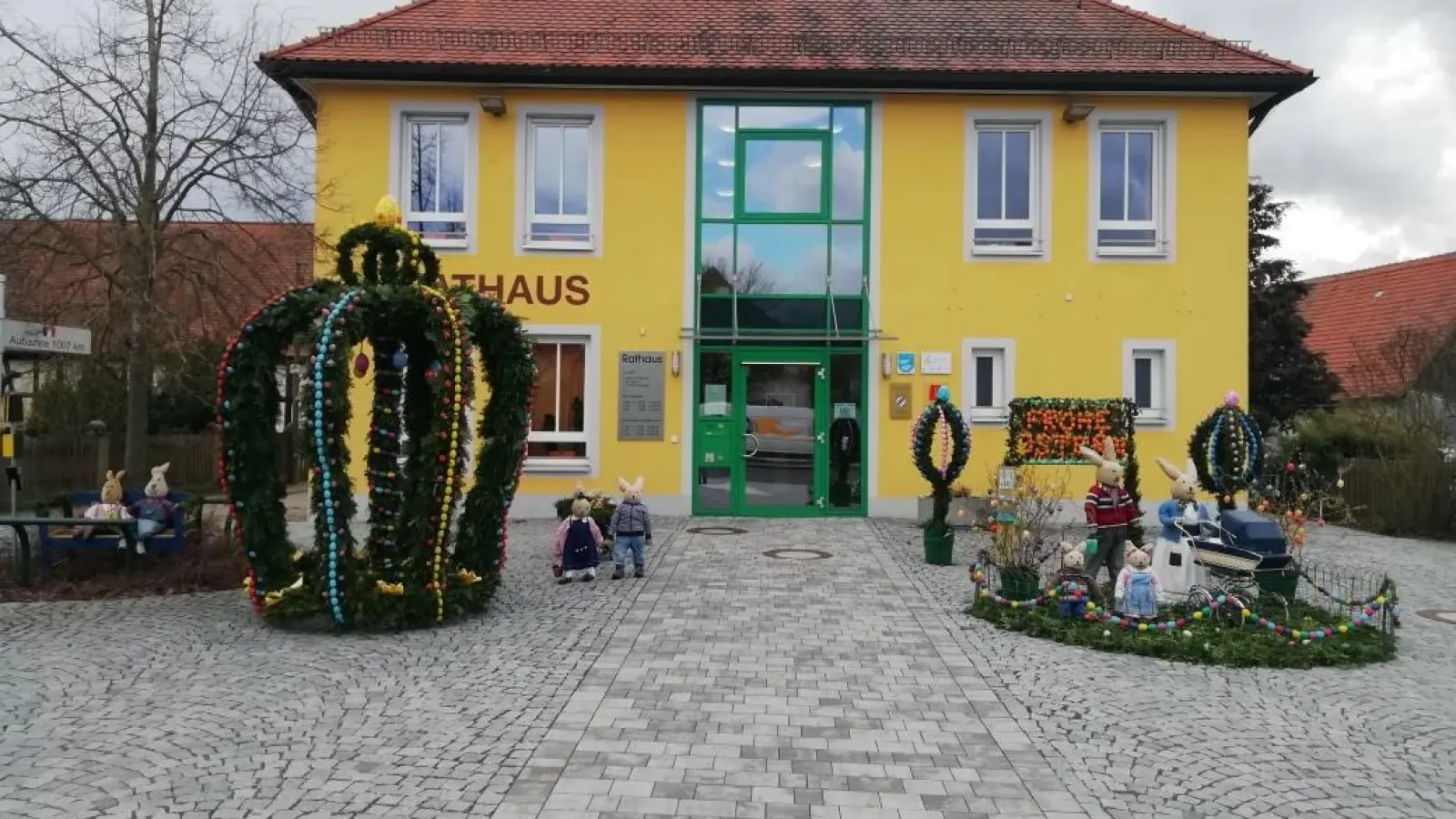 Flanieren oder Sitzen statt Hoppeln: Die Colmberger Osterkrone steht wieder vor dem Rathaus, bewacht von einer Osterhasenfamilie.  (Foto: Meinhard Schernau)