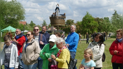 Die Teilnehmer eines Rundgangs durch die Streuobstwiesen schauen sich Kokons der Seidenraupe an. Im Hintergrund ist das Krähennest zu erkennen, ein Spielturm, der bei Kindern sehr beliebt ist. (Foto: Helmut Meixner)