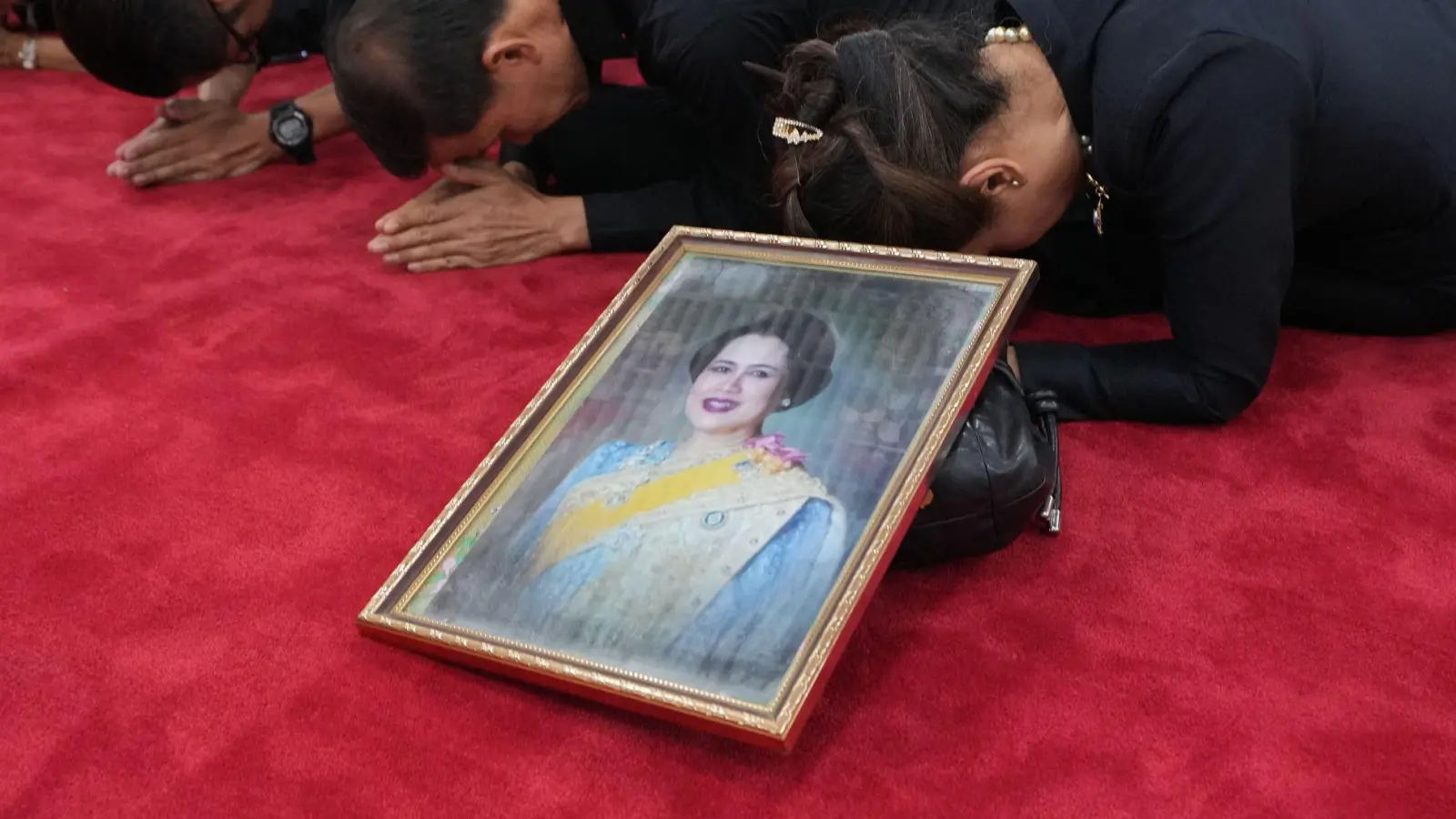 Trauernde beten in Bangkok mit einem Porträt der Königinmutter Sirikit. (Foto: Sakchai Lalit/AP/dpa)