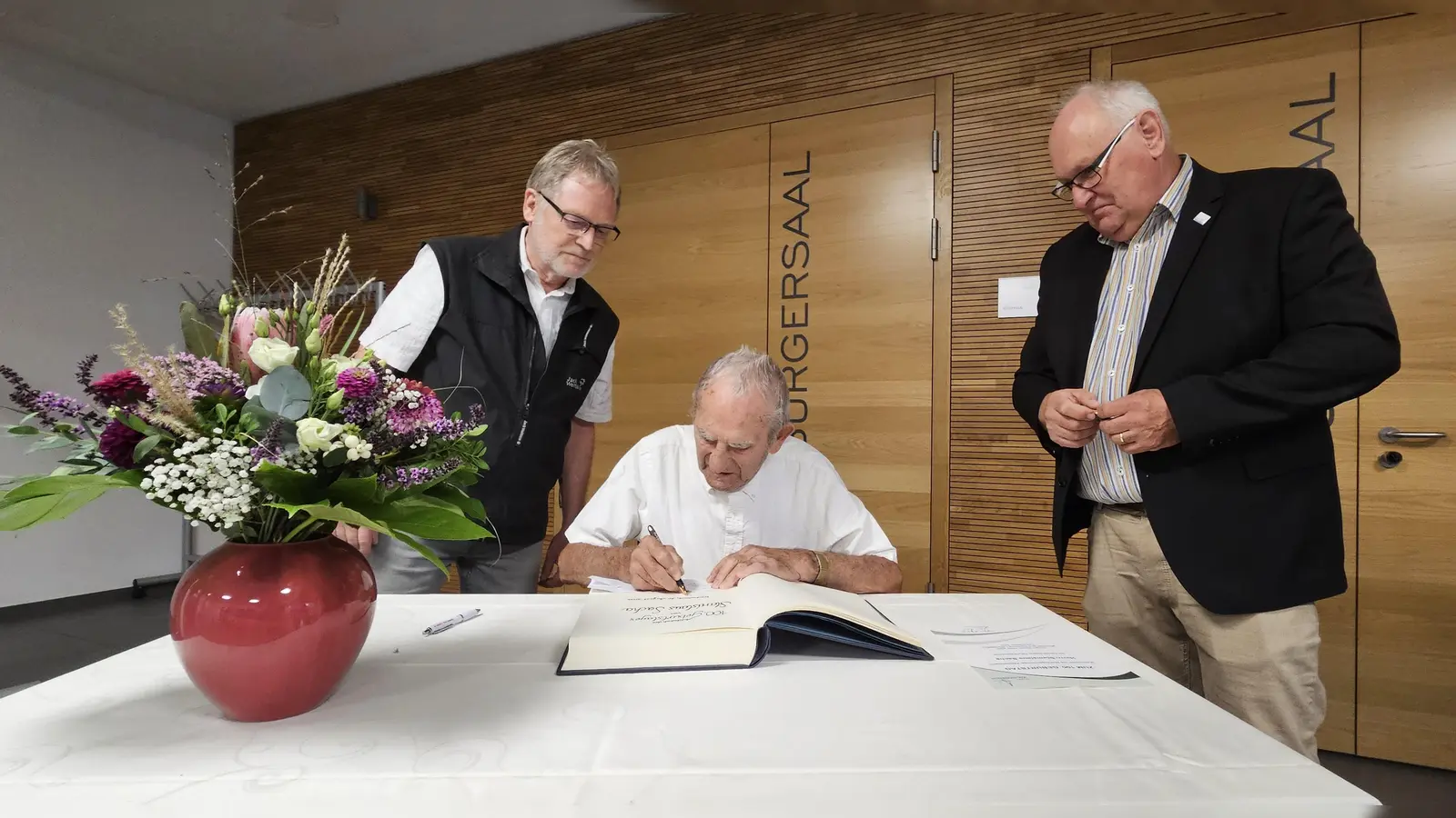 Stanislaus Sacha beim Eintrag ins Goldene Buch der Gemeinde Weidenbach. Sein Sohn Helmut (links) und Bürgermeister Willi Albrecht attestierten ihm. (Foto: Wolfgang Grebenhof)