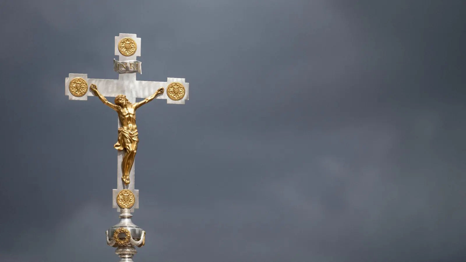 Ein Kruzifix vor dunklen Wolken. (Foto: Marijan Murat/dpa)