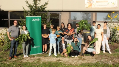 Schulleiter Patrick Seitz, AOK-Mittelfranken-Direktorin Thea Götz und die Schülerinnen und Schüler der Kombiklasse 7/8 (von links) bei der Ernte von Gemüse. (Foto: AOK Bayern/Jasmin Weber)