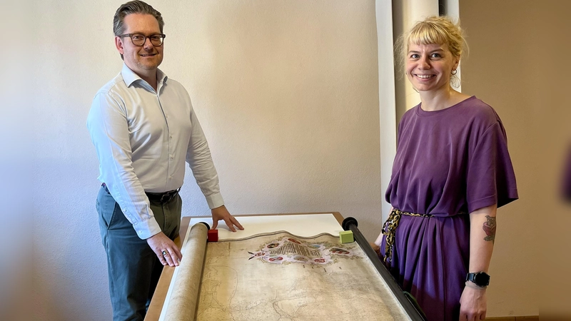 Christian Mantsch und die Restauratorin Nina Steininger mit einer bereits gereinigten Karte, auf der eine kolorierte Handzeichnung aus dem Jahr 1728 zu sehen ist. (Foto: Alexander Schmidtke)