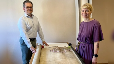 Christian Mantsch und die Restauratorin Nina Steininger mit einer bereits gereinigten Karte, auf der eine kolorierte Handzeichnung aus dem Jahr 1728 zu sehen ist. (Foto: Alexander Schmidtke)