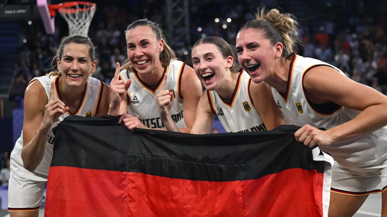 Feiern mit der Fahne: Die 3x3-Basketballerinnen. (Foto: Sina Schuldt/dpa)