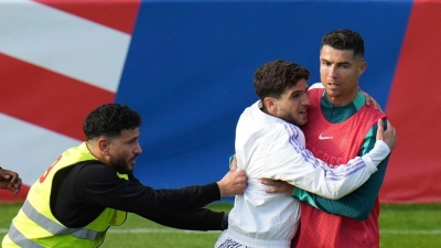 Ein Fan sprintet in Gütersloh auf den Trainingsplatz und umarmt Portugals Superstar Cristiano Ronaldo. (Foto: Hassan Ammar/AP/dpa)