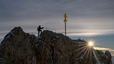 Das Gipfelkreuz ist mit Hunderten Stickern beklebt und muss restauriert werden. (Foto: Peter Kneffel/dpa)
