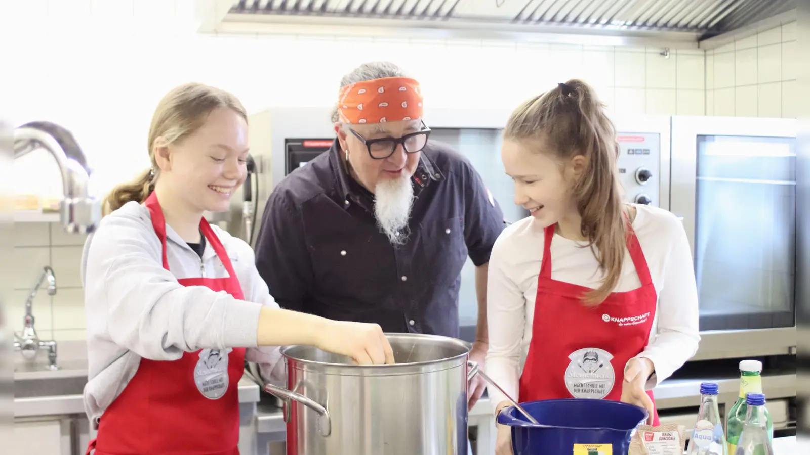 Sternekoch Stefan Marquard schaut den Schülerinnen über die Schulter: Marie Hauf und Vanessa Sindel (von links) bereiten die vegane und laktosefreie Soße auf Hafermilch-Basis für die Frikadellen zu. (Foto: Pauline Held)