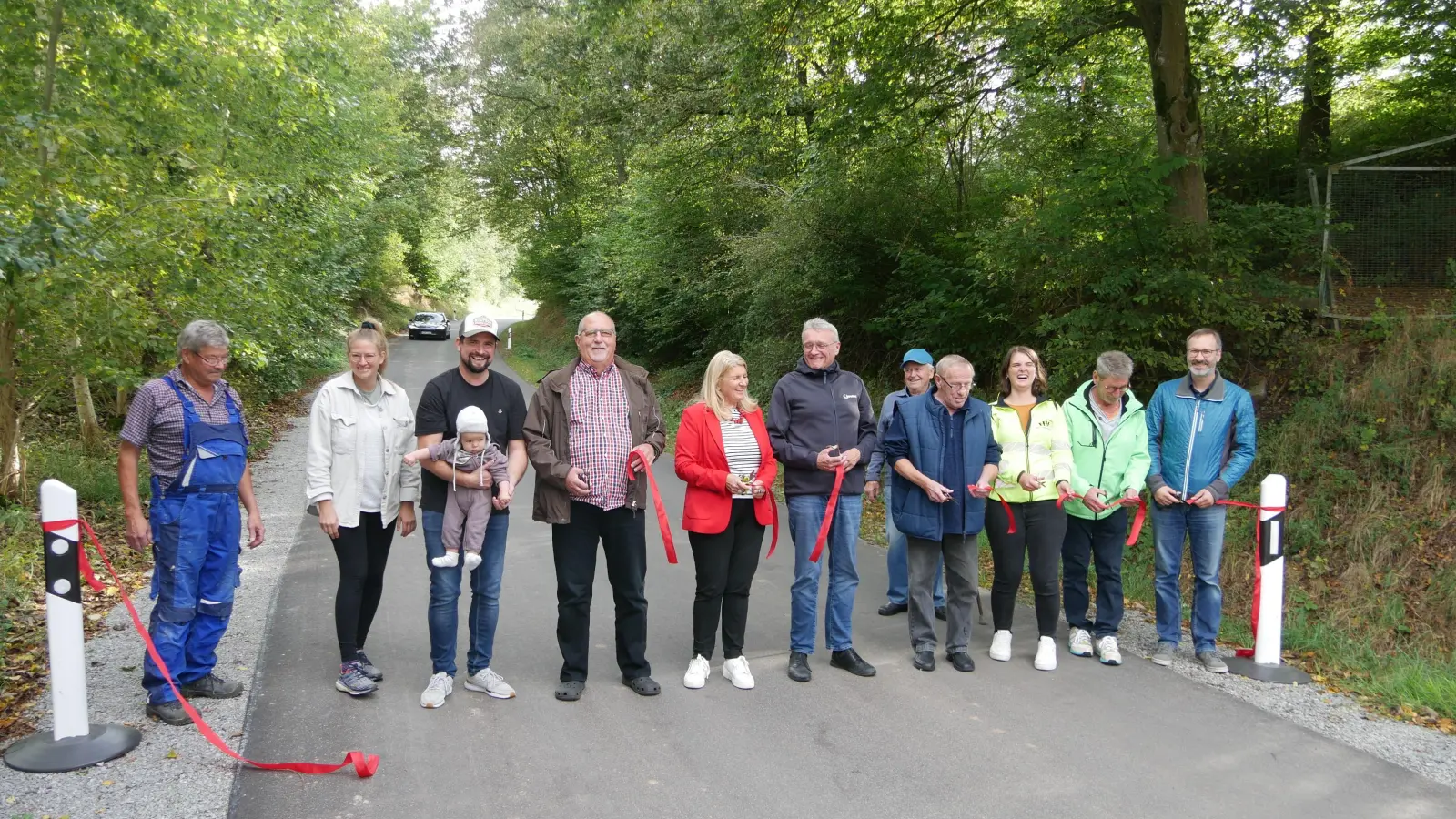 Vertreter und Vertreterinnen aus Mosbach (darunter der zweitjüngste Ortsteilbewohner Jonah), der Gemeinde und der beteiligten Firmen weihten nach erfolgter Sanierung die Gemeindeverbindungsstraße von Mosbach in Richtung Oberulsenbach wieder ein. (Foto: Ulli Ganter)