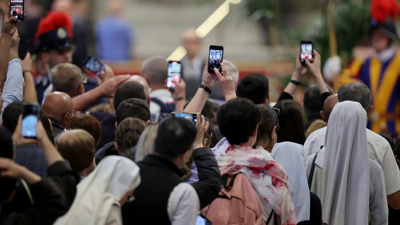 Mit den Smartphones machen Gläubige ein Foto vom toten Papst. (Foto: Christoph Reichwein/dpa)