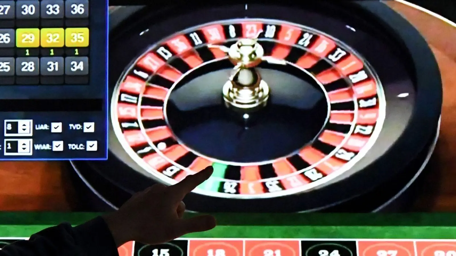 Ein Mann steht vor einem Bildschirm mit einer Seite für Online-Roulette. (Foto: Carsten Rehder/dpa)