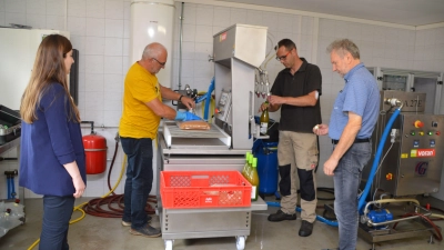 Der Vorsitzende des Obst- und Gartenbauvereins Gerhard Knöchlein (im gelben Shirt) füllt Apfelsaft in den Beutel, Björn Reiß mit Hilfe von Bürgermeister Gerhard Eichner (rechts) in Flaschen. Allianzmanagerin Theresia Pöschl beobachtet zufrieden, was sie da gefördert hat. (Foto: Johannes Zimmermann)